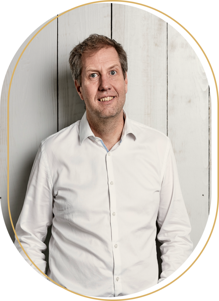 Porträt von Daniel Schmedding eines Mannes in weißem Hemd vor hellem Holzhintergrund