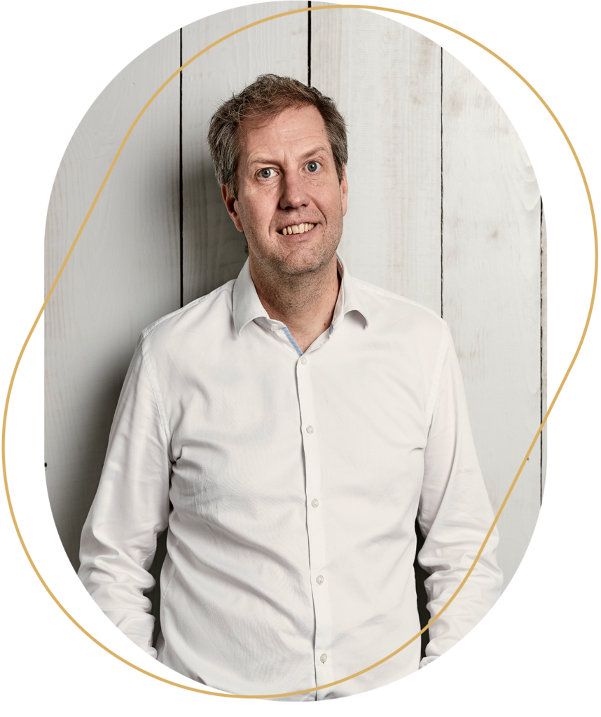 Porträt von Daniel Schmedding eines Mannes in weißem Hemd vor hellem Holzhintergrund